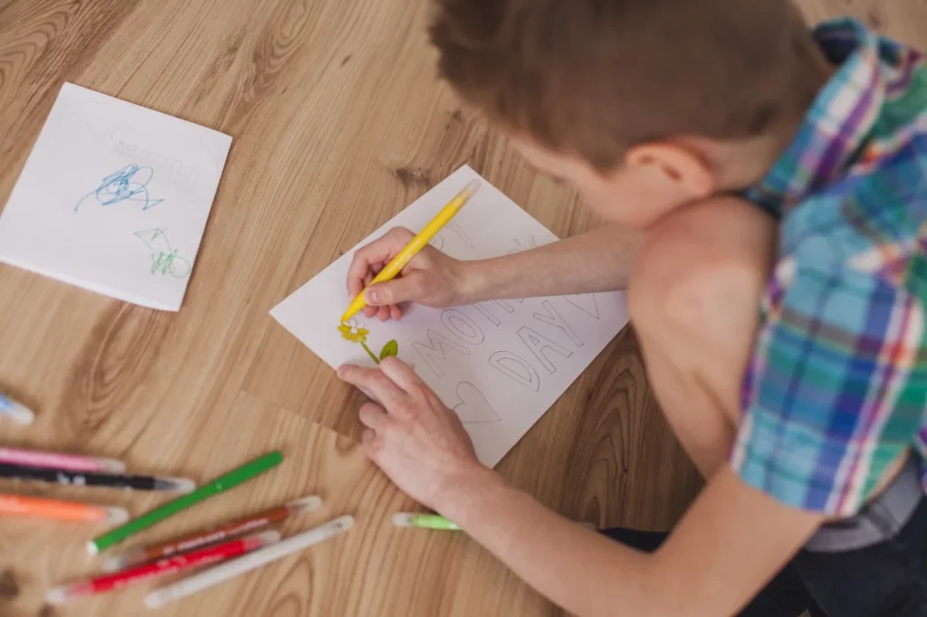 Ein Junge zeichnet auf ein Blatt Papier.